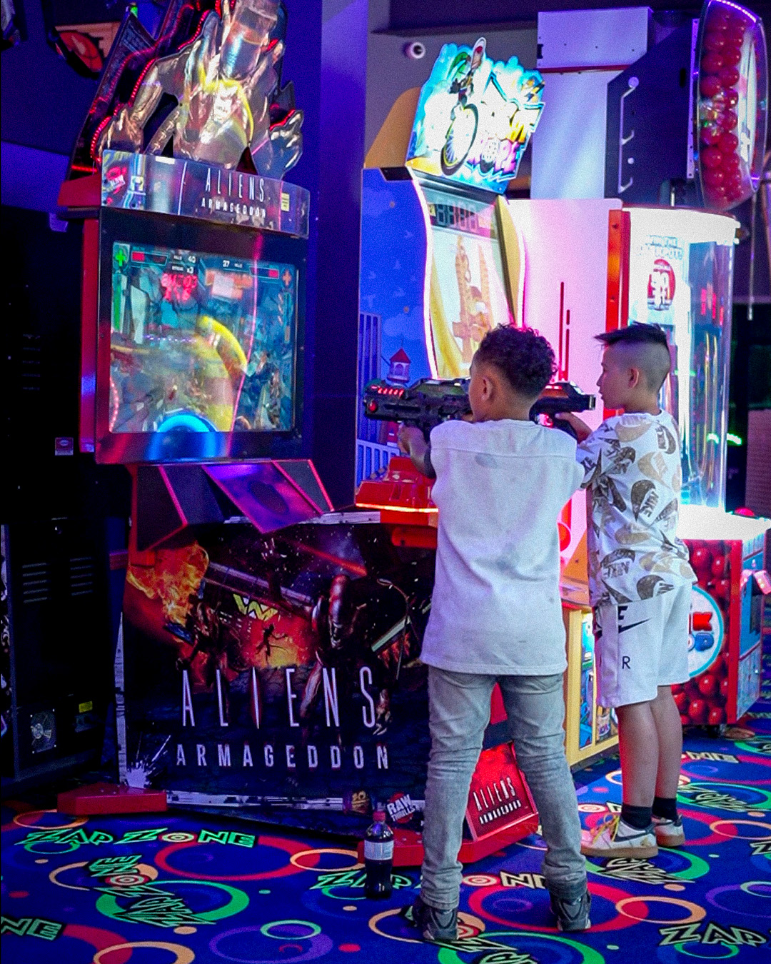 Kids playing shooter arcade game Aliens Armageddon.